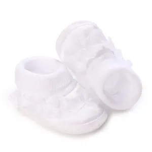 Gros plan de chaussures blanches pour bébé fille avec dentelle délicate et texture douce.