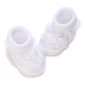 Gros plan de chaussures de princesse blanches pour bébé avec dentelle délicate et poignets