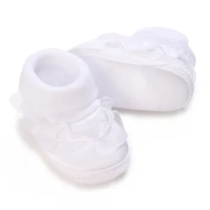 Gros plan sur la dentelle blanche délicate et les volants des chaussures de bébé