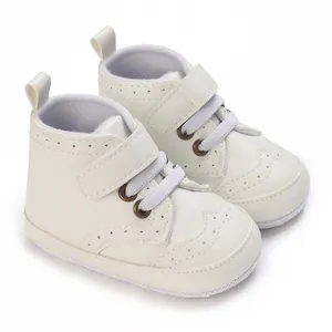 Bottines blanches pour bébé à semelle souple avec détails brogue et fermeture velcro.