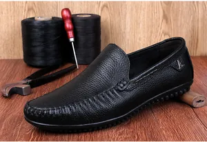 Detailansicht der schwarzen Herren-Leder-Slipper mit handwerklichen Schuhmacherwerkzeugen