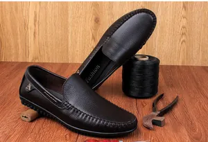 Handwerkliche Präsentation brauner Leder-Loafer mit Schuhmacherwerkzeug auf Holzgrund