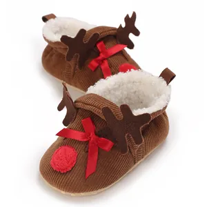 Close-up of reindeer themed baby booties featuring red bow and plush white lining
