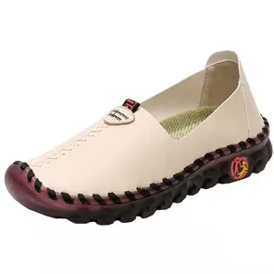Detail of a beige leather flat shoe with burgundy sole and hand-stitched accents.