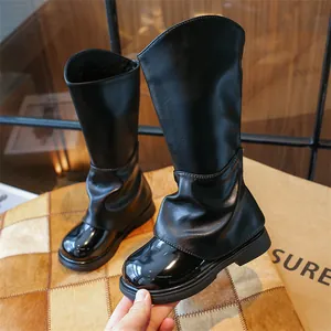 Détail de bottes hautes noires pour filles avec bout brillant et design chic plissé