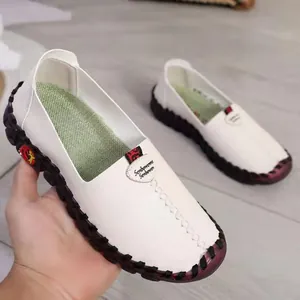 Detailed view of white leather casual loafers featuring black hand-stitched edge design