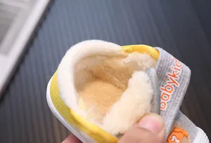 Close-up of plush warm lining in yellow and grey baby winter toddler shoes.