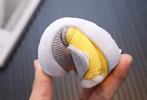 Macro view showing the extreme flexibility of the soft white sole on plush baby shoes.