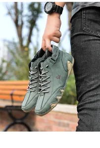 Detailed view of green suede octopus-sole boots held in hand against outdoor park background