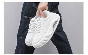 Detailed side view of white chunky sneakers with air cushion sole held by a person in denim