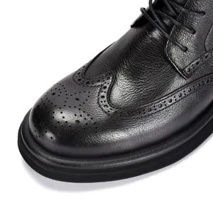 Dettaglio ravvicinato di stivali Brogue in pelle nera con eleganti trafori a coda