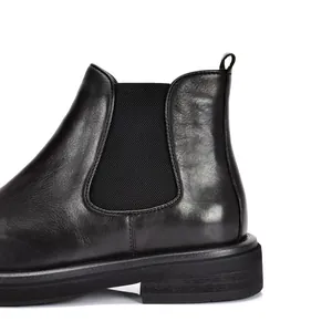 Detail view of black leather Chelsea boot showing elastic panel and thick sole