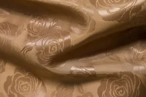 Makro-Detail der goldfarbenen Stofftextur mit Rosenprägung für modische Herrenhemden