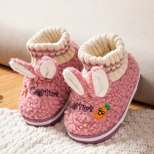 Nahaufnahme von rosa flauschigen Babypantoffeln mit Hasenohren und Karottenstickerei