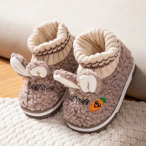 Nahaufnahme von niedlichen Baby-Baumwollhausschuhen mit Hasenohren und Karotten-Stickerei.