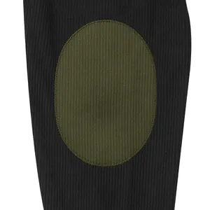 Detailed macro view showing olive green oval patch on black corduroy fabric texture