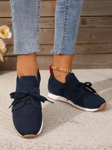 Atmungsaktive marineblaue Mesh-Sneaker mit dekorativer Schleife und dicker weißer Sohle.