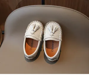 Gros plan de mocassins en cuir blanc pour enfants avec glands et coutures détaillées