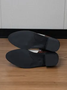 Gedetailleerde macro-weergave van de antislip zwarte rubberen zool en slangenmotief van dameslaarzen