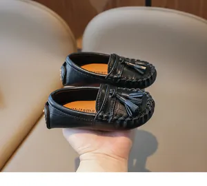 Gros plan de mocassins en cuir noir pour enfants avec détails de glands et coutures raffinées