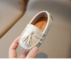 Gros plan de mocassins en cuir blanc pour enfants avec glands et coutures classiques