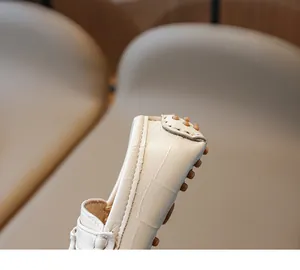 Gros plan sur la texture crocodile blanche et la semelle antidérapante du mocassin enfant