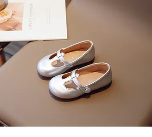 Close-up of silver girls' Mary Jane shoes with velcro strap on a leather surface