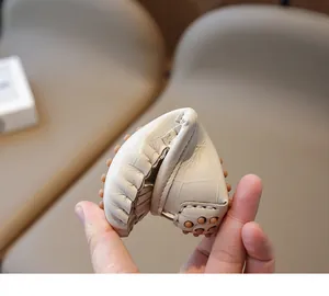 Gros plan d'un mocassin en cuir beige souple pour bambin montrant la semelle à picots