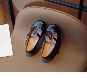 Top-down view showing black girls' T-strap leather Mary Janes on a brown chair