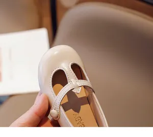 Close-up of beige round-toe girl's leather shoe with T-strap detail