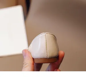 Detailed close-up of the reinforced heel stitching on kids' beige leather shoes