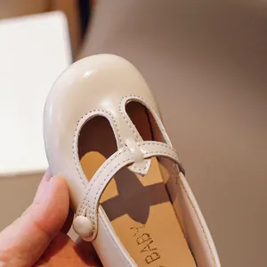 Close-up of beige round-toe Mary Jane toddler shoes with T-strap and button detail