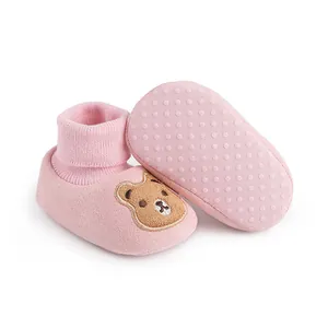 Detail of pink knitted baby shoes with soft non-slip soles and cartoon bear embroidery