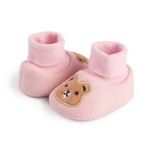 Close-up of pink baby soft-sole booties featuring a cute brown bear embroidery detail.