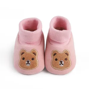 Close-up detail of pink soft sole baby shoes featuring an embroidered cartoon bear