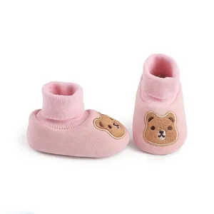 Close-up detail of soft pink baby winter booties featuring cute brown bear embroidery