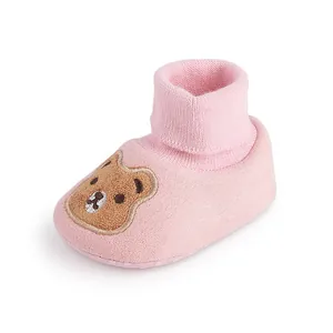 Close-up of pink baby soft sole cotton shoes with embroidered cartoon bear detail.