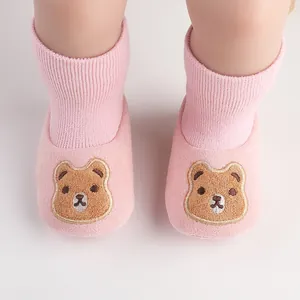Detailed view of pink knitted baby shoes featuring a cute embroidered brown bear character