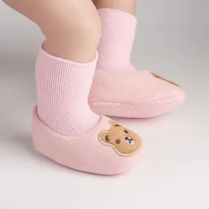 Close-up of pink baby booties with adorable bear embroidery and soft anti-slip soles.