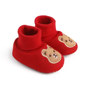 Close-up of red baby winter booties featuring a cute embroidered cartoon bear design