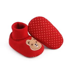 Detailed view of red indoor baby shoes with cartoon bear patch and non-slip rubber soles