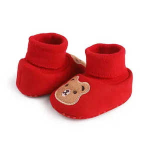Close-up of red infant soft-sole indoor shoes with a cute embroidered bear patch