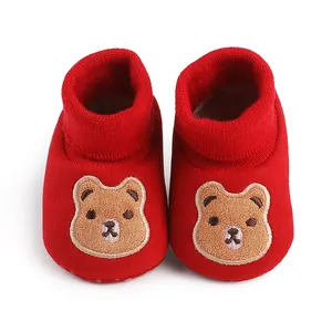 Close-up detail of red baby soft-sole shoes with cute brown bear embroidery pattern