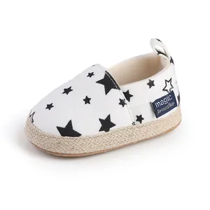 Detalle de zapato de bebé blanco con estrellas negras y suela de esparto tejida