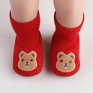 Detailed macro view of red baby indoor shoes with cute cartoon bear embroidery design.