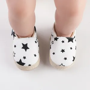 Vista superior detallada de zapatos para bebé blancos con estrellas negras y suelas de yute
