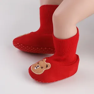 Detailed view of red soft-soled baby sock shoes featuring a cute brown cartoon bear design