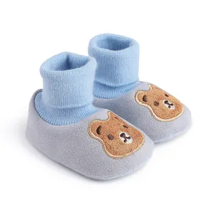 Close-up view of soft knit baby booties featuring cute brown bear embroidery detail