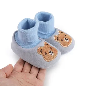 Detailed view of soft blue and grey baby booties with a cute embroidered cartoon bear