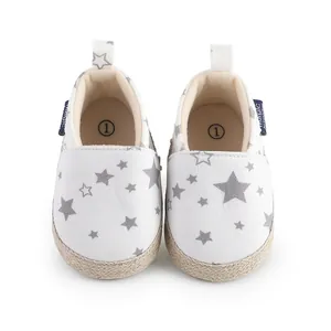 Vista superior de zapatos de bebé blancos con estrellas grises y bordes de suela de cuerda